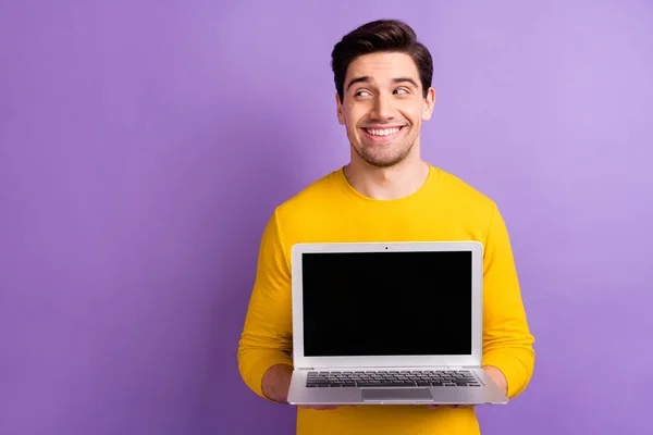 Портрет задоволеного молодого чоловіка рук тримає дисплей ноутбука, щоб виглядати порожнім простором ізольовано на фіолетовому кольоровому фоні — стокове фото