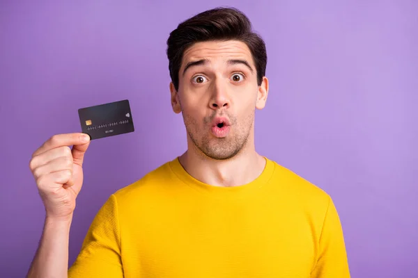 Foto van jonge knappe jongen verbaasd geschokt hold credit card betaling geïsoleerd over violette kleur achtergrond — Stockfoto