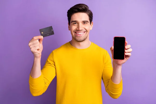 Foto av glad man hand hålla betalkort visar visning strålande leende isolerad på violett färg bakgrund — Stockfoto