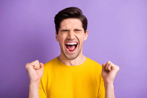 Foto de joven emocionado loco sonriente alegre hombre positivo gritando mantenga los puños en la victoria aislado sobre fondo de color violeta — Foto de Stock