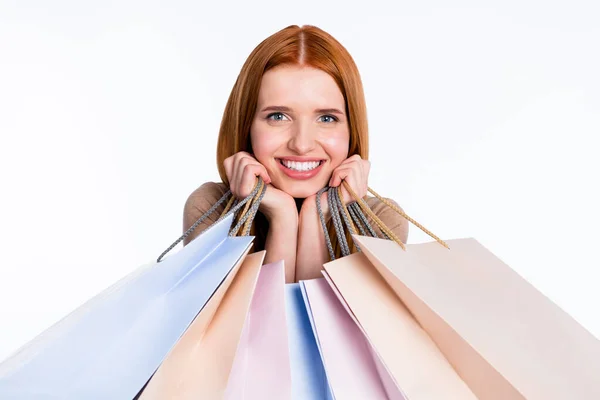 Foto de mujer pelirroja bastante soñadora camisa beige sosteniendo bolsas de tienda brazos mejillas sonriendo aislado color blanco fondo —  Fotos de Stock