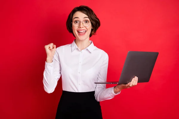 Foto retrato de la mujer de negocios manteniendo portátil gesto como ganador aislado vibrante fondo de color rojo — Foto de Stock