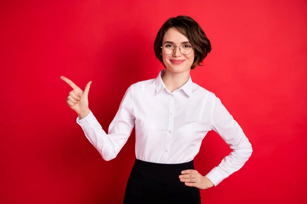 Foto de feliz sorrindo positivo linda menina em óculos apontar dedo copyspace anúncio isolado no fundo de cor vermelha — Fotografia de Stock