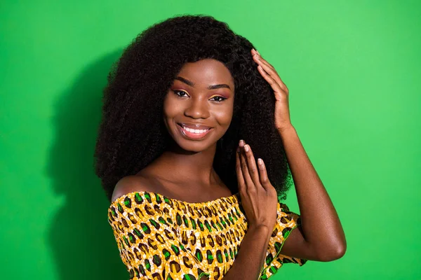 Foto de joven hermosa positiva encantadora sonriente encantadora afro chica cuidando el cabello aislado sobre fondo de color verde — Foto de Stock