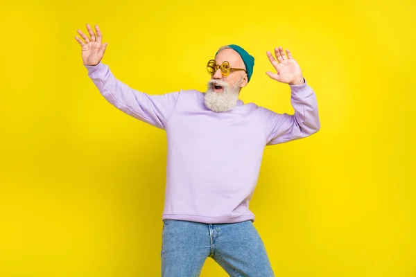 Foto de hombre maduro dulce funky vestido púrpura jersey gafas de vista sonriente baile aislado color amarillo fondo —  Fotos de Stock