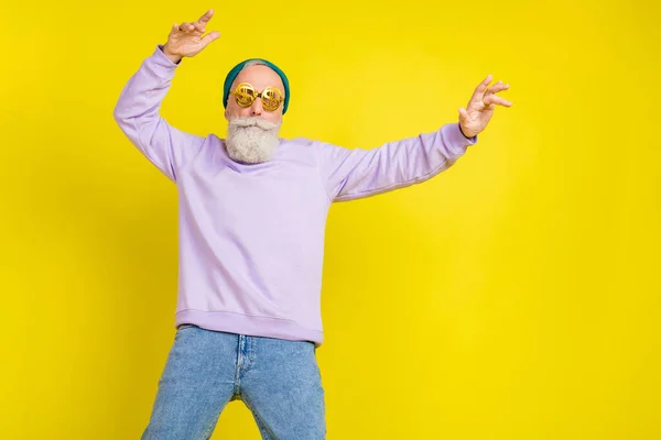 Photo of cute cool age gentleman wear violet sweater headwear eyeglasses dancing isolated yellow color background — Stock Photo, Image