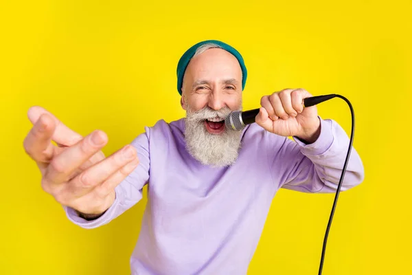 Фото смішного позитивного віку джентльмен носить фіолетовий светр головний убір, танцюючий спів ізольований жовтий колір фону — стокове фото