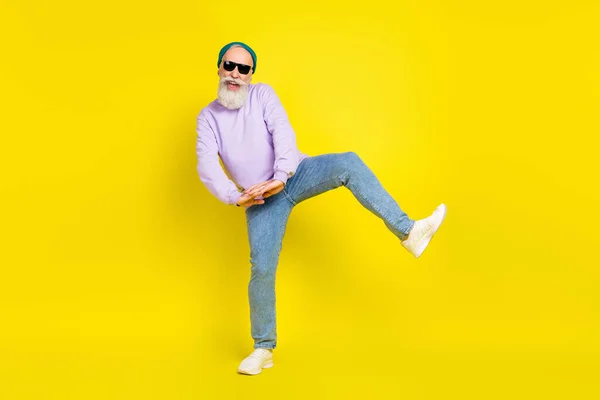 Fénykép aranyos édes kor úriember viselni lila pulóver fejfedő sötét szemüveg mosolygós tánc elszigetelt sárga szín háttér — Stock Fotó