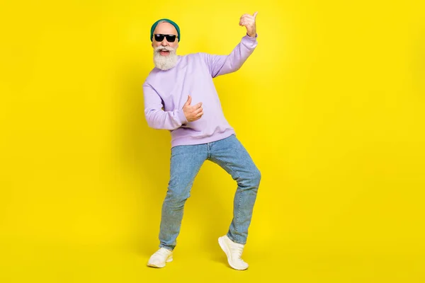 Foto de homem maduro bonito vestido púrpura pulôver óculos de cabeça dançando tocar guitarra isolado cor amarela fundo — Fotografia de Stock