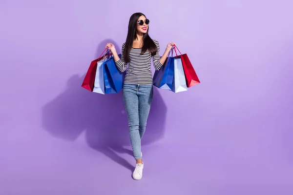 Foto em tamanho completo de jovem positivo bom humor mulher shopaholic ir andar olhar copyspace isolado no fundo cor violeta — Fotografia de Stock