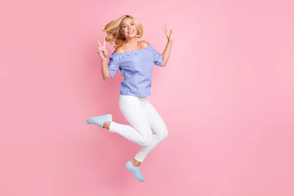 Pleine longueur vue de la taille du corps de belle fille aux cheveux ondulés joyeux sautant montrant v-signe isolé sur fond rose couleur pastel — Photo