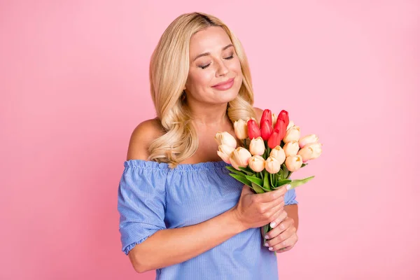 Retrato de atractiva mujer alegre sosteniendo en las manos oliendo tulipanes frescos aislados sobre fondo de color pastel rosa —  Fotos de Stock