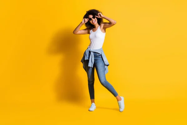 Foto de larga duración de piel oscura mujer feliz usar gafas apretada chaqueta de la cintura aislada en el fondo de color amarillo brillante — Foto de Stock