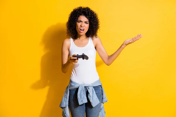 Foto van overstuur donkere huid vrouw dragen strakke taille jas afkeer spel houden joystick geïsoleerd op fel gele kleur achtergrond — Stockfoto