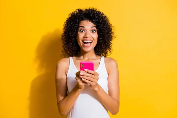 Fénykép a vicces izgatott fiatal sötét bőr hölgy viselni fehér kislemez gépelés modern eszköz elszigetelt sárga szín háttér — Stock Fotó