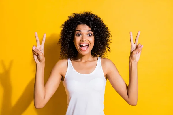 Retrato de piel oscura positiva excitada boca abierta dos dedos de los brazos muestran v-signo aislado sobre fondo de color amarillo — Foto de Stock