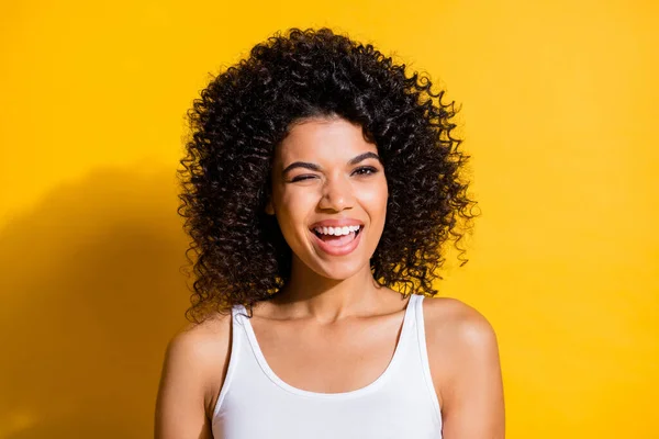 Photo of shiny adorable young dark skin lady wear white singlet winking isolated yellow color background — Stock Image Photo of shiny adorable young dark skin lady wear white singlet winking isolated yellow color background Stock Picture