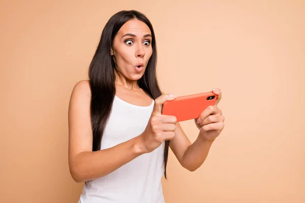 Photo portrait of amazed woman holding phone vertically in two hands isolated on pastel beige colored background — Stock Photo, Image