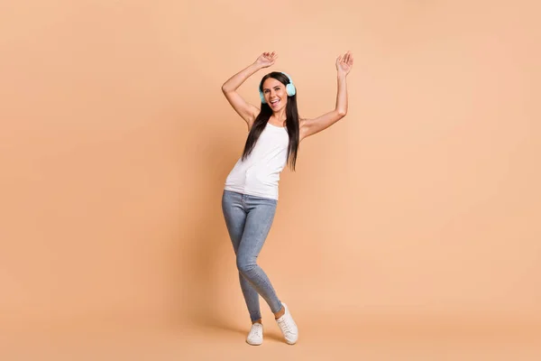 Retrato fotográfico de chica en auriculares bailando aislada sobre fondo de color beige pastel —  Fotos de Stock