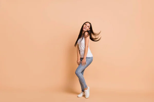 Full size profilo foto di ottimistica bruna ragazza danza cantare usura bianco top jeans scarpe da ginnastica isolato su sfondo beige — Foto Stock