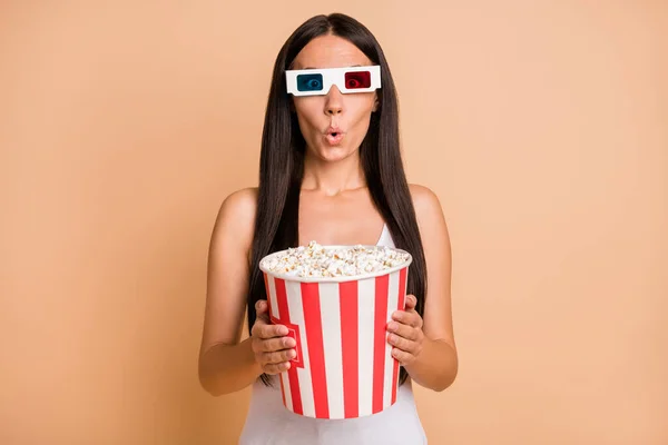 Photo portrait of amazed girl in 3d glasses holding popcorn bag isolated on pastel beige colored background — Stock Photo, Image