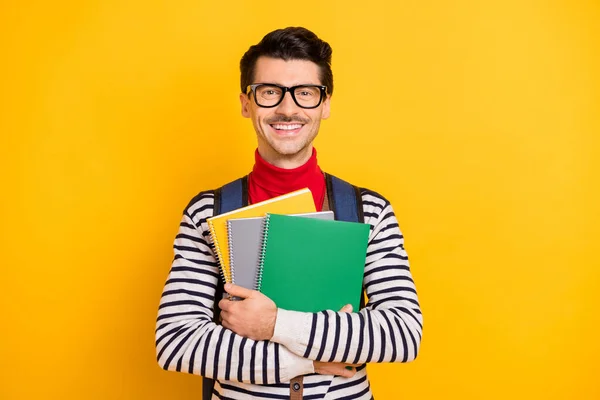 Retrato de las manos de la persona satisfecha sostiene copybooks llevar mochila radiante sonrisa aislada sobre fondo de color amarillo —  Fotos de Stock