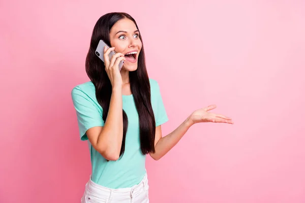 Фото молодой счастливой взволнованной улыбающейся позитивной девушки смотреть копипространство говорить по телефону изолированы на розовом фоне — стоковое фото