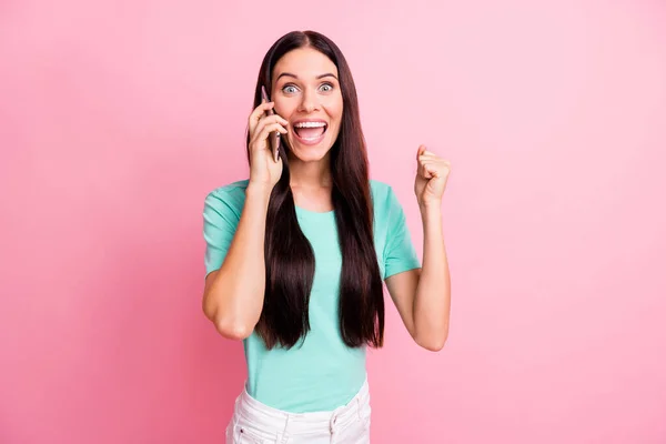 Fénykép a fiatal vonzó szép jó hangulat izgatott lány beszélni telefonon emelje öklöt győzelem elszigetelt rózsaszín színű háttér — Stock Fotó
