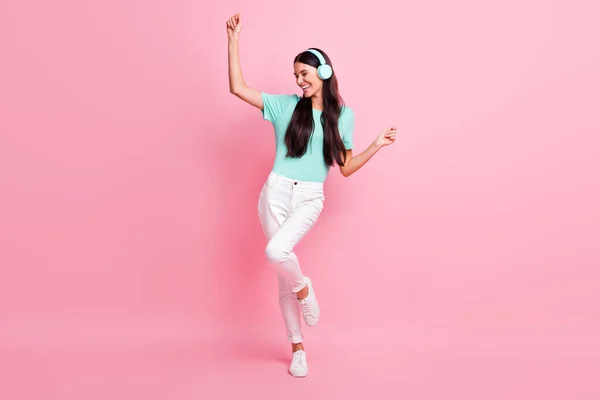 Foto de tamaño completo de la joven feliz chica emocionada positiva escuchar música en los auriculares bailando aislado en el fondo de color rosa —  Fotos de Stock