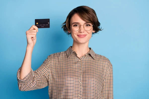 Foto de adorável jovem braço segurando cartão de débito bancário sorriso desgaste xadrez isolado no fundo de cor azul — Fotografia de Stock