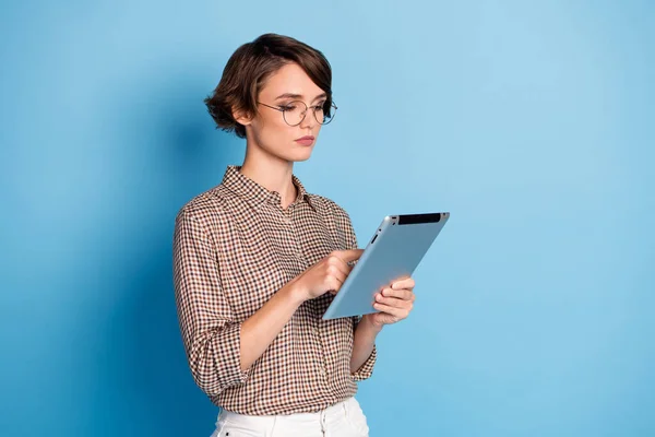 Photo de focalisé jeune femme regarder lire tenir tablette freelance porter des lunettes isolées sur fond de couleur bleue — Photo