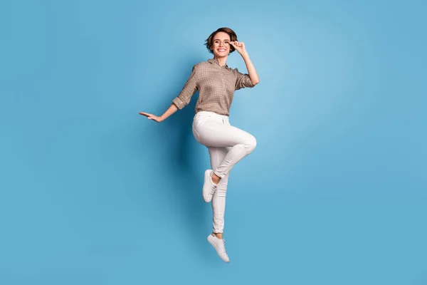 Foto de corpo inteiro de adorável menina despreocupada pulando mão tocar óculos isolados no fundo de cor azul — Fotografia de Stock