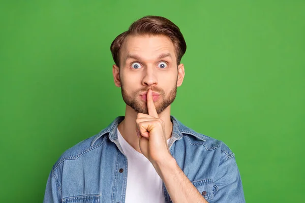 Foto de sorprendido sorprendido hombre sorprendido cubrir la boca con el silencio del dedo sin palabras aislado sobre fondo de color verde — Foto de Stock