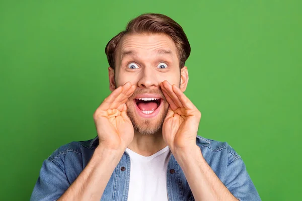 Foto de feliz emocionado alegre sonriente guapo hombre gritando información de noticias aislado en el fondo de color verde — Foto de Stock