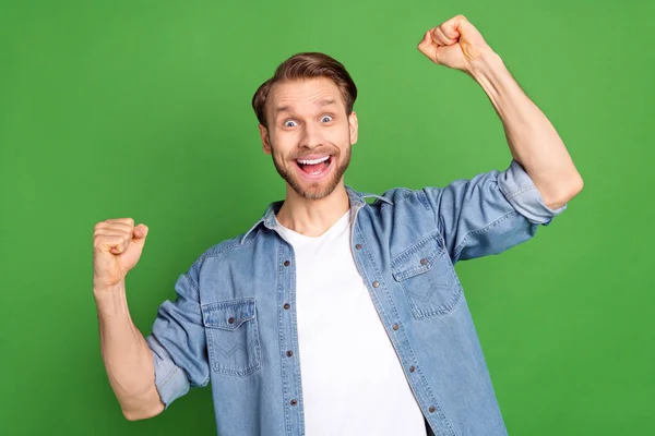 Photo de jeune heureux excité funky drôle homme lever les poings dans la victoire triomphe de succès isolé sur fond de couleur verte — Photo