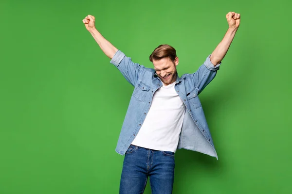 Фотопортрет насолодженого чоловіка жестикулює як переможець в повсякденному одязі ізольований яскраво-зелений кольоровий фон — стокове фото
