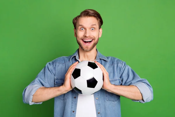Фотопортрет веселого человека, держащего футбольный мяч улыбающимся изолированным ярко-зеленым цветом фона — стоковое фото
