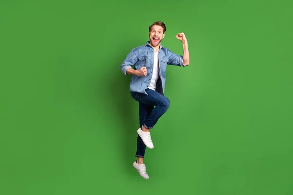 Full length body size photo of young guy jumping happy gesturing like winner cheerful isolated vivid green color background — Stock Photo, Image