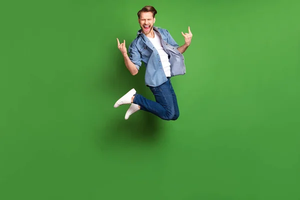 Pleine longueur taille du corps photo de jeune gars sautant haut montrant signe en métal lourd réjoui isolé fond de couleur verte vibrante — Photo