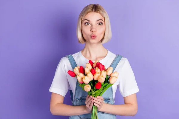 Foto de bonito optimista corto peinado rubio dama celebrar flores golpe beso desgaste blanco camiseta aislada sobre fondo violeta — Foto de Stock