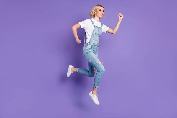 Teljes méretű profil fotó szép optimista rövid frizura szőke hölgy fut kopás fehér póló teljes elszigetelt lila háttér — Stock Fotó