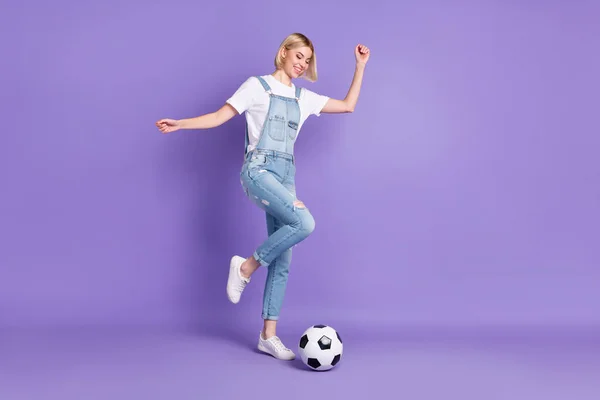 全长侧面照片，年轻女孩开心积极的微笑踢球比赛与紫色背景隔离 — 图库照片