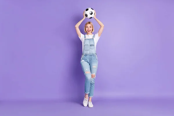 Foto de corpo inteiro de menina animada feliz sorriso positivo jogar bola de futebol captura isolada sobre fundo cor violeta — Fotografia de Stock