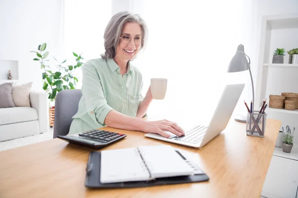 Foto de perfil de persona franca alegre mano sostener taza de té radiante sonrisa mirada portátil escribir correo electrónico en el interior — Foto de Stock