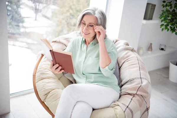 Фото очаровательного веселого человека, сидящего на стуле руки сенсорные очки книги чтения имеют хорошее настроение выходные в помещении — стоковое фото