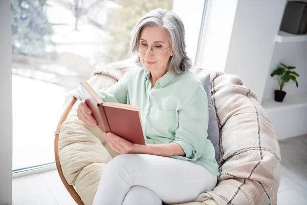 Portré elég pozitív személy ül a szék kezét tartja olvasás érdekes könyv élvezze hétvégi otthon beltérben — Stock Fotó