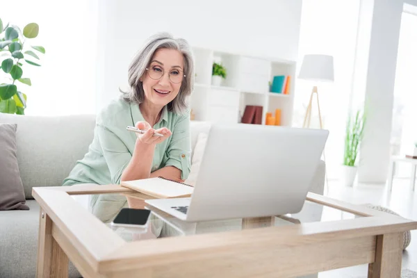 照片上积极坦率的女士坐在沙发扶手笔上解释说笔记本电脑在室内视频聊天 — 图库照片