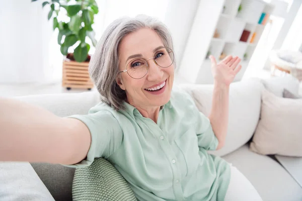 Foto van positieve ouder persoon zitten op de bank selfie arm palmen tonen directe vrije tijd weekend binnen — Stockfoto