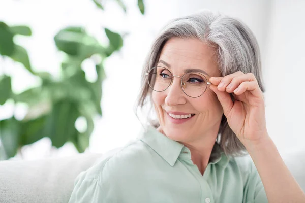 Fénykép elégedett idős nő kéz touch szemüveg néz érdekelt távoli sugárzó mosoly szabadidő beltérben — Stock Fotó