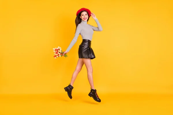 Foto lateral de perfil de tamaño completo de lady jump up walk hold tulipanes usan falda de cuero cuello alto rayado aislado sobre fondo de color amarillo —  Fotos de Stock